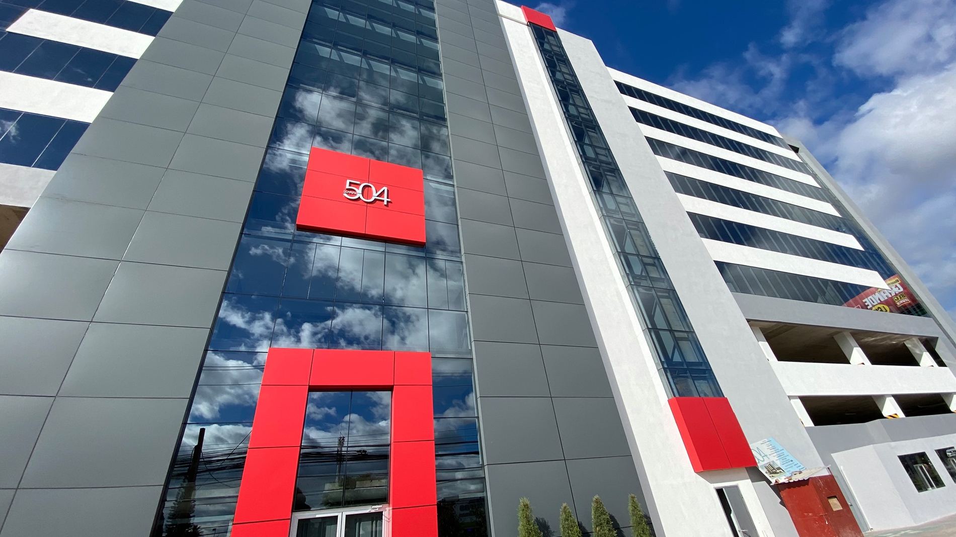 Torre Suyapa 504 vista desde abajo en ángulo, con su señalética roja '504' sobre la fachada de vidrio