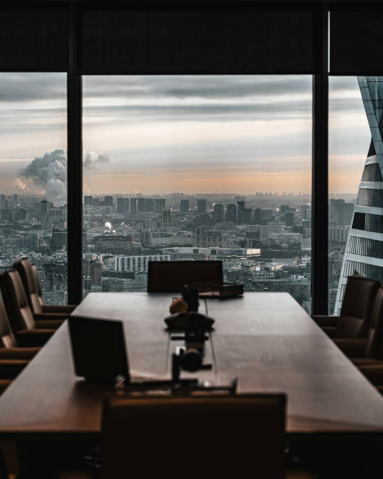 Sala de juntas con mesa de madera y vista panorámica a la ciudad al atardecer